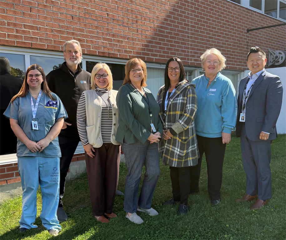 Group standing out front of hospital celebrating the signing of the purchase agreement